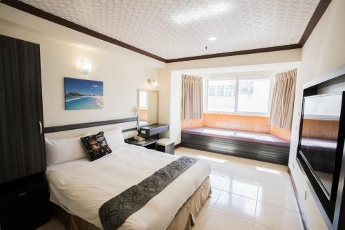 una camera d'albergo con un letto e una grande finestra di Kenting Maldives Hotspring Hotel a Città Vecchia di Hengchun