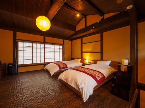a bedroom with two beds and a large window at 100 years old traditional Kyoto Machiya townhouse - K's Villa in Kyoto