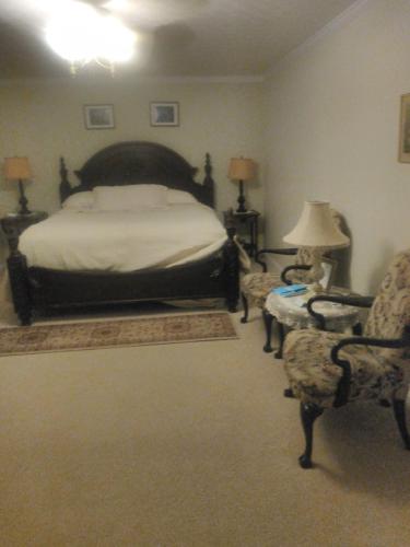 a bedroom with a bed and two chairs at Serenity Hill b&b in Sloans Crossing