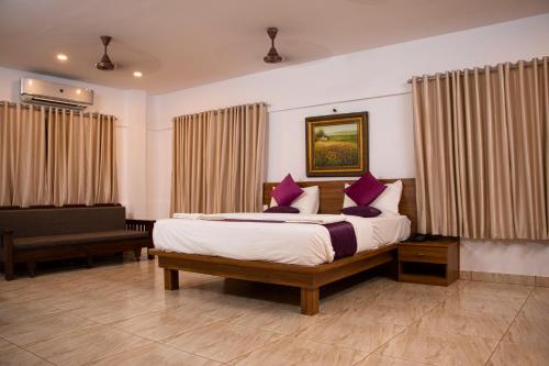 a bedroom with a bed with purple pillows and a piano at Shoolin Resorts in Manipala
