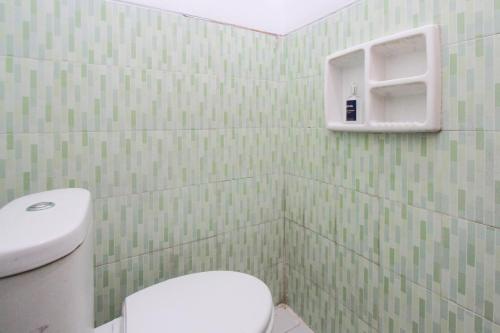een badkamer met een wit toilet en groene betegelde muren bij OYO 2042 Zam Zam Family Syariah in Ketapang