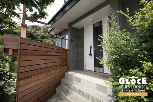 a front door of a house with a wooden fence at GLOCE 葉山 サーファーズログハウス l HAYAMA Surfers Log house in Hayama