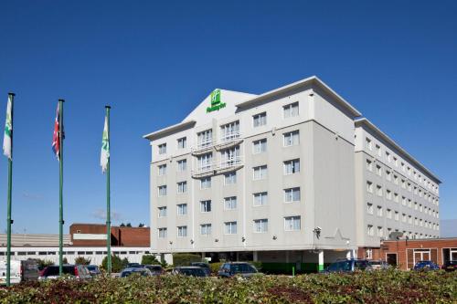 a white hotel with cars parked in a parking lot at Holiday Inn Basildon by IHG in Basildon