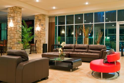 a living room with leather couches and a red stool at Holiday Inn Temple - Belton by IHG in Temple