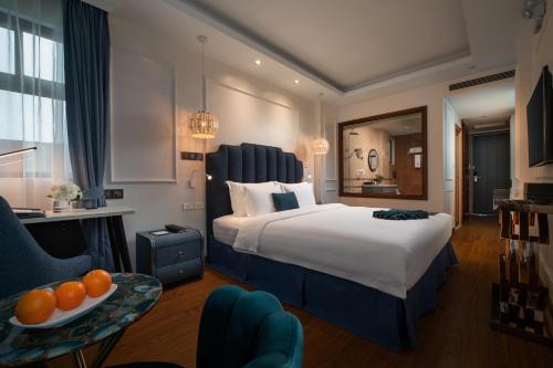 ein Hotelzimmer mit einem großen Bett und einem Tisch in der Unterkunft Dahlia Hotel Hanoi in Hanoi