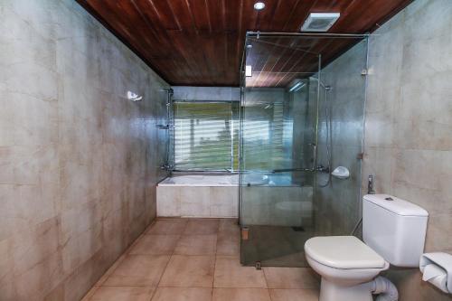 a bathroom with a glass shower and a toilet at Maresia Beach Villa in Wadduwa