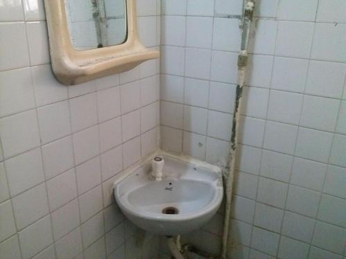 a white bathroom with a sink and a mirror at Capital Guest House in Kolkata