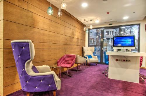 a waiting room with purple chairs and a tv at Holiday Inn Plovdiv, an IHG Hotel in Plovdiv