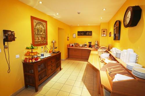 a kitchen with yellow walls and a counter with plates at Hotel Berlioz EuroAirport Basel - Mulhouse - Freiburg in Saint-Louis