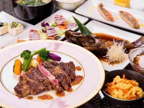 a table topped with plates of food with meat and vegetables at エコヴィレッジ西表 Eco Village Iriomote in Iriomote
