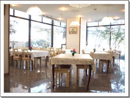 a dining room with tables and chairs and windows at Hotel New Yutaka in Izumi-Sano