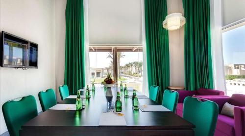 a dining room with a table and green chairs at Park Inn by Radisson Hotel and Residence Duqm in Duqm