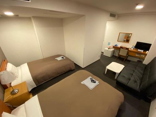 a room with a bed and a couch and a desk at Hotel New Yutaka in Izumi-Sano