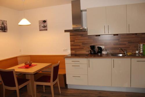 une cuisine avec des placards blancs et une table en bois dans l'établissement Steinhof, à Val di Mezzo