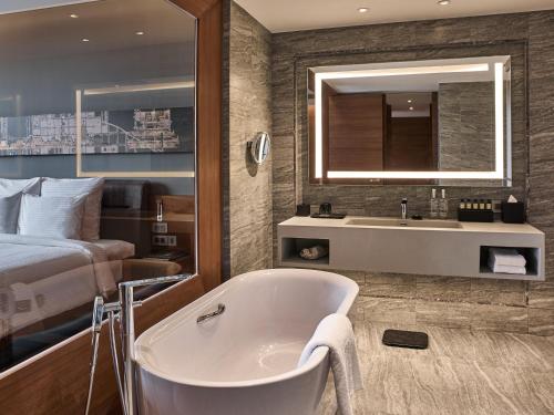 a bathroom with a tub and a bed and a sink at Mingalar Mandalay Hotel in Mandalay