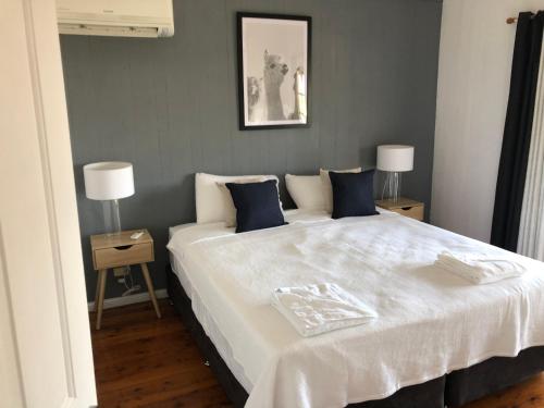 a bedroom with a large white bed with blue pillows at Bellbird House in Cessnock