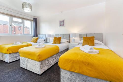 - 2 lits dans une chambre avec des draps jaunes dans l'établissement 4 Bedrooms Cosy Family Home, Super-Fast Wi-Fi, Free Parking, The Saddlers Gateway, à Walsall