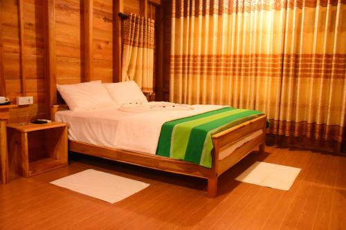 a bedroom with a bed with a green and white blanket at Wild Lake Side in Udawalawe