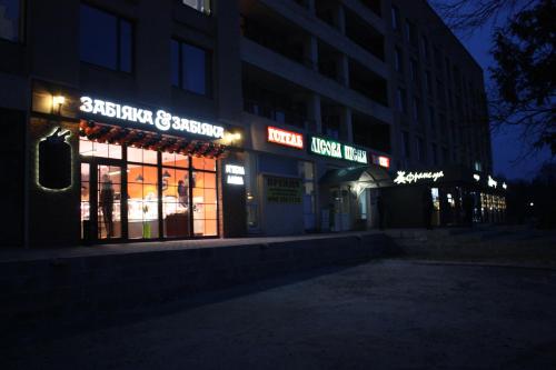 un bâtiment avec des panneaux de néon sur son côté la nuit dans l'établissement RP hotel Лісова пісня, à Kovel