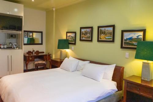 a bedroom with a bed with white sheets and pictures on the wall at Calitzdorp Country House in Calitzdorp