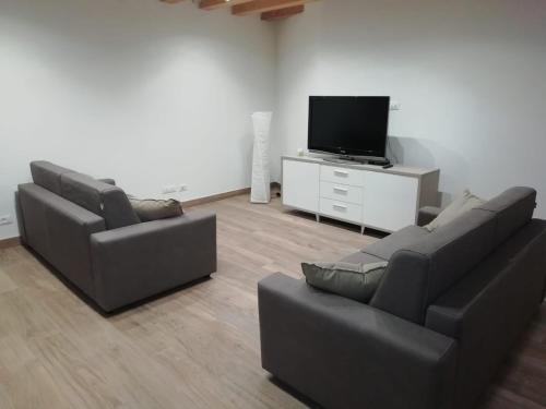 uma sala de estar com 2 sofás e uma televisão de ecrã plano em Calle Michelangelo Apartments em Veneza