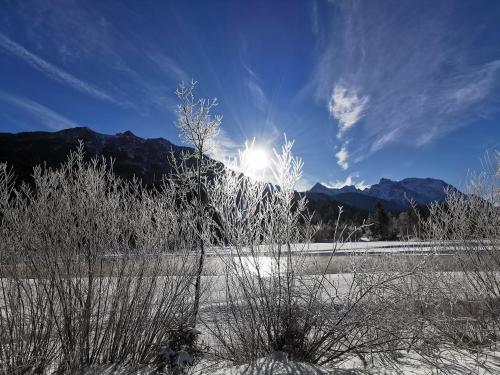 a snow covered field with the sun in the sky at Gästehaus Simon in Krün