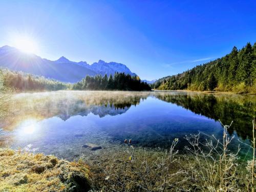 a lake in the mountains with the sun reflecting in the water at Gästehaus Simon in Krün