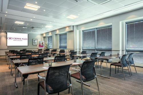a conference room with tables and chairs and a screen at Crowne Plaza Birmingham NEC by IHG in Bickenhill