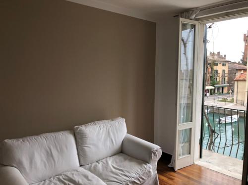 a white couch in a living room with a large window at Lacisivm Lake View in Lazise