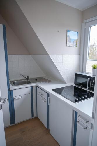 a white kitchen with a sink and a stove at Haus Kamp in Tinnum