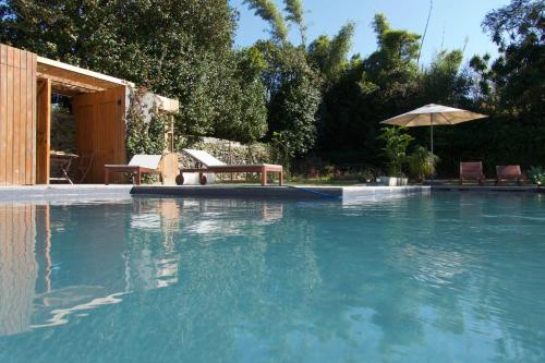 a swimming pool with a table and an umbrella at #Areias Houses 7 in Furnas