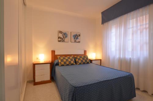 sypialnia z niebieskim łóżkiem i 2 szafkami nocnymi w obiekcie Apartamentos Xulia w mieście Raxo