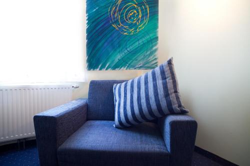 una silla azul con una almohada a rayas en una habitación en Gasthof Hotel Lang, en Rauchwart im Burgenland