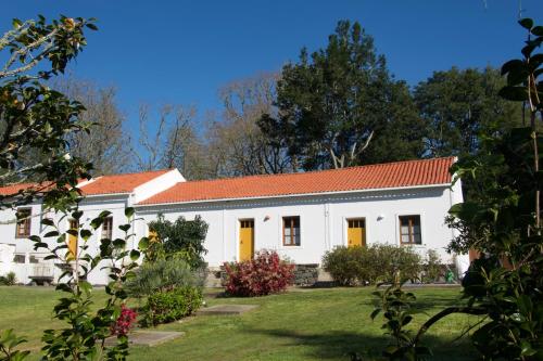 a white building with orange doors and a yard at #Areias Houses 7 in Furnas