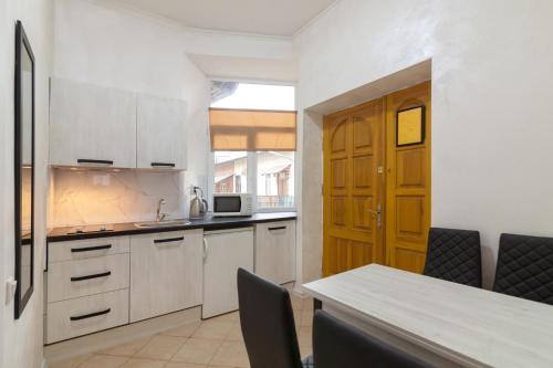 リヴィウにあるLEOGRAND Apartments Panteleimona Kulisha 27のキッチン(白いキャビネット、テーブル、椅子付)