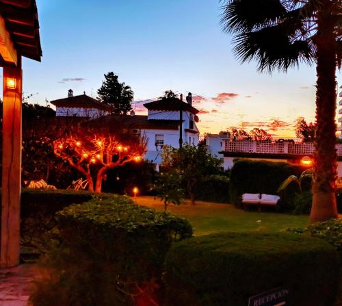a house with a palm tree in front of a sunset at Hostal Boutique Los Geranios del Pinar in Torremolinos