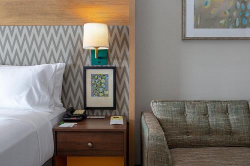 a bed and a chair in a hotel room at Holiday Inn Toledo - Maumee I-80/90 by IHG in Maumee