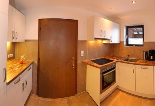 eine Küche mit weißen Schränken und einer Holztür in der Unterkunft Gästehaus Wildauer in Schlitters