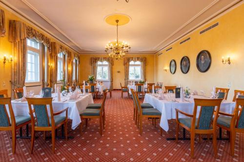 a restaurant with white tables and chairs and a chandelier at Jagdschloss Hotel Niederwald in Rüdesheim am Rhein