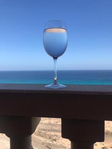 a glass of wine sitting on a rail near the beach at Your Ocean Suite in Costa Calma
