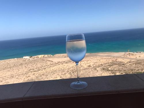 a wine glass sitting on a ledge overlooking the ocean at Your Ocean Suite in Costa Calma