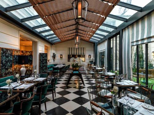 a restaurant with tables and chairs in a room with windows at J.K. Place Paris in Paris