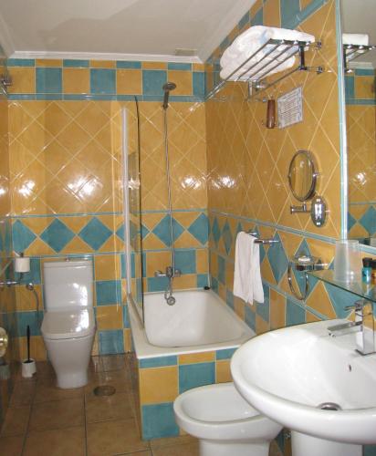 a bathroom with a toilet and a tub and a sink at Boutique Hotel Pueblo in Benalmádena