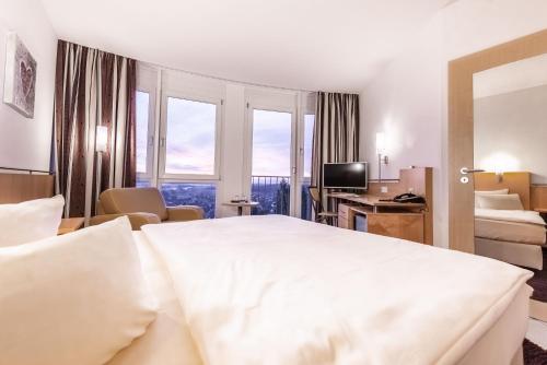 a hotel room with a large white bed and windows at Raitelberg Resort in Wüstenrot