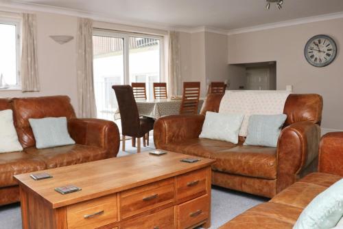 a living room with leather furniture and a table at TOWN CENTRE apartment with parking in Padstow
