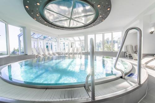 a swimming pool in a building with a large window at Raitelberg Resort in Wüstenrot