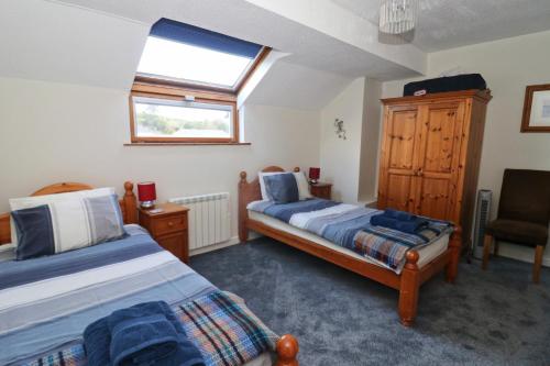 a bedroom with two beds and a window and a chair at TOWN CENTRE apartment dogs welcome in Padstow