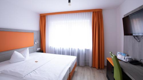 a hotel room with a bed and a large window at Hotel Elite in Karlsruhe