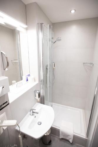 a white bathroom with a sink and a shower at Hotel Elite in Karlsruhe