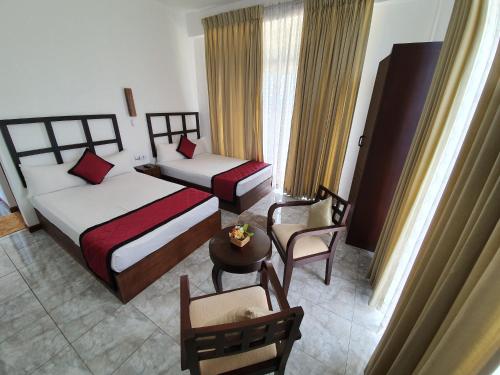 a hotel room with two beds and a table and chairs at Tranquil Villa in Nuwara Eliya